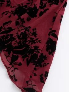Nahaufnahme von burgunderfarbenem Netzgewebe mit eleganten schwarzen Samtblumenflocken
