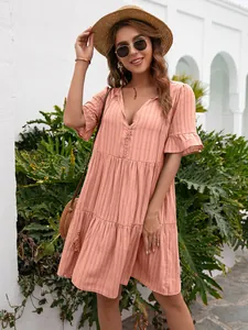 Model posing in a pink tiered V-neck summer dress with ruffle sleeves and button details