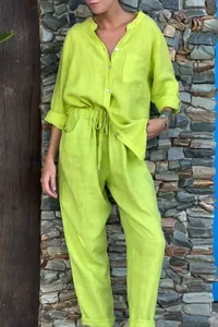 Élégant ensemble en lin vert citron pour femme porté devant un mur en pierre naturelle