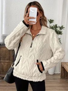 Détail d'un sweat-shirt en peluche blanche texturée avec demi-fermeture éclair et poches.