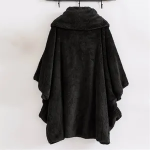 Vista posteriore di un comodo poncho in pile nero oversize con cappuccio e consistenza morbida