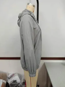 Detaillierte Seitenansicht eines grauen Outdoor-Windbreakers mit Kapuze auf einer Puppe.
