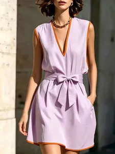 Dettaglio di un elegante abito lilla senza maniche scollo a V con bordo arancione e fiocco