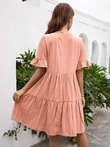 Back view of a casual peach tiered summer dress with ruffle sleeves in a garden setting.