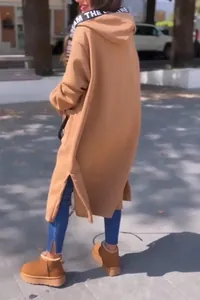 Achteraanzicht van een lange camel oversized fleece hoodie jas met zijsplitjes aan kap.