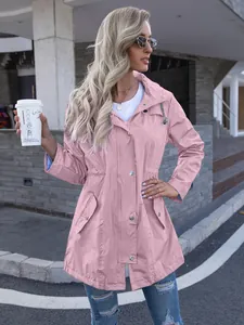 Outdoor street style shot of a woman in a pink mid-length hooded raincoat with zipper