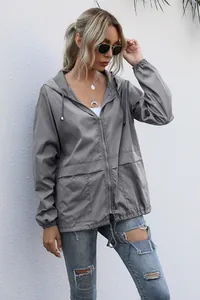 Outdoor detail of a women's lightweight gray hooded windbreaker jacket with zipper