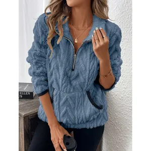 Detailopname van een blauwe pluizige damessweatshirt met een halve rits en kabeltextuur.