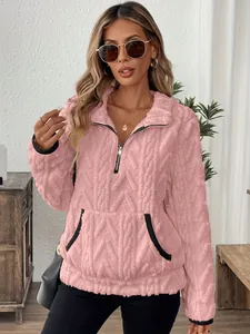 Gros plan d'un sweat à capuche rose en peluche avec texture jacquard et demi-zip.