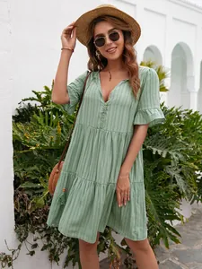 Detailed look of a sage green tiered V-neck dress with button accents and ruffled sleeves.