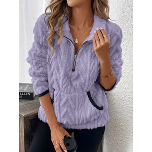 Detailopname van een paars fleece sweatshirt met halve rits en contrasterende zakdetail.