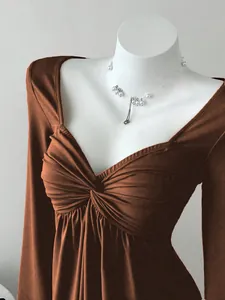 Gros plan d'un haut marron à manches longues et col en V avec un design torsadé élégant