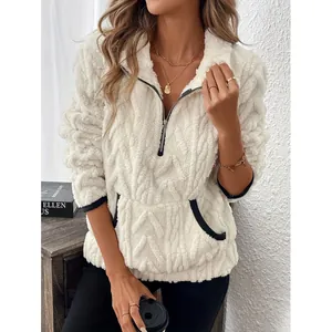 Detailweergave van een witte donzige fleece trui met halve rits en zwarte contrastbiezen