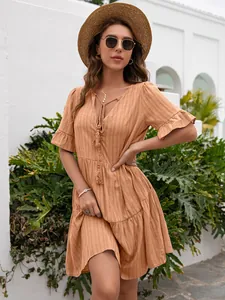 Detail view of ginger V-neck summer dress with ruffle sleeves and tassel drawstring.