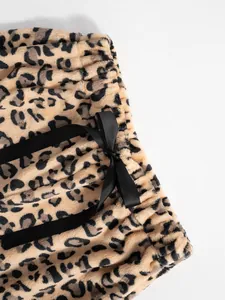 Macro detail of soft plush leopard print trousers featuring a black satin bow drawstring