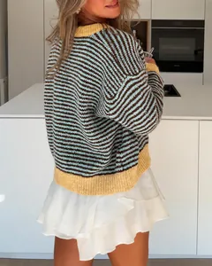 Detail of striped knit sweater with yellow ribbed hem on model in modern kitchen