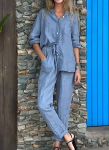 Mannequin portant un ensemble en coton et lin bleu clair sur un fond de mur en pierre