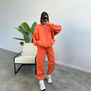Oversized orange fleece zip-up hoodie and joggers set for women in minimalist setting
