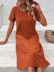 Détail d'une robe ample orange en coton et lin avec col rond et poches pratiques.