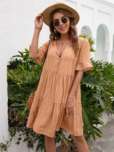 Detailed shot of bohemian apricot V-neck dress with ruffled sleeves and tiered skirt
