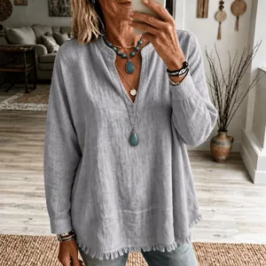 Gros plan sur le détail du bas effiloché d'une blouse à manches longues en couleur bleu clair.