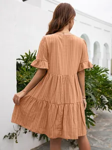 Back view of a relaxed apricot tiered mini dress featuring textured fabric and ruffle sleeves
