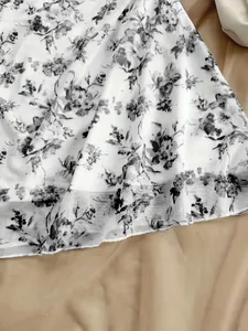 Dettaglio del motivo floreale nero e dell'orlo delicato su un vestito estivo bianco