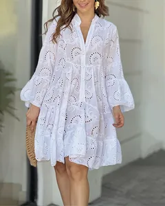 Detalle de un vestido blanco con cuello en V, bordado calado y mangas de campana