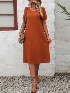 Détail d'une robe midi orange en coton et lin avec poches dans un cadre extérieur décontracté
