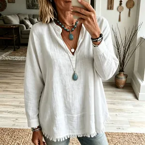 Détail d'une blouse blanche décontractée à col en V avec ourlet effiloché et coupe ample