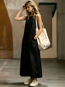 Sleeveless black maxi dress with side pockets worn with a stylish canvas tote bag