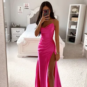 Pink satin slip dress with high slit and pleated detail in elegant bedroom setting.