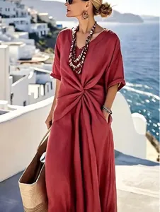 Elegante abito lungo bohémien rosso con dettaglio intrecciato in vita in riva al mare