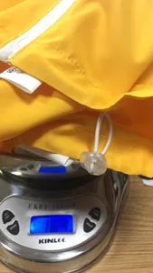 Detailed view of lightweight yellow waterproof jacket on a digital scale showing 182.4g