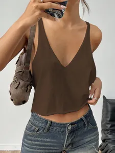Dettaglio di un top in maglia marrone con scollo a V abbinato a jeans e borsa.