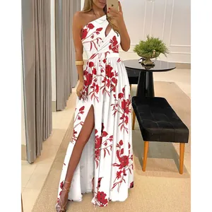 Detail of white one-shoulder maxi dress with red floral print and high leg slit.