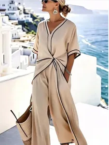 Elegante completo estivo beige con profili a contrasto e nodo in vita in riva al mare