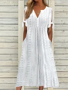 Vue détaillée de la broderie anglaise blanche et du col en V avec boutons décoratifs.