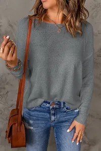 Detailed shot of a grey knitted long-sleeve sweater paired with casual denim jeans