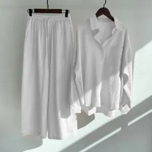 Detailed view of white cotton linen shirt and wide-leg pants set hanging on a wall