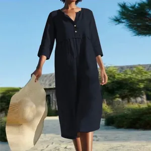 Model wearing a navy cotton linen midi dress with buttons in a sunny outdoor setting