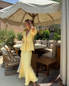 Elegant woman in yellow puff sleeve top and skirt set standing in an outdoor patio.