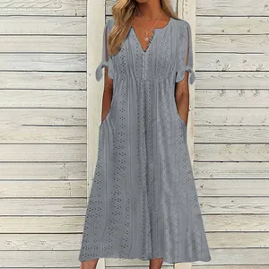 Détail d'une robe grise à col en V avec broderie anglaise et manches nouées élégantes
