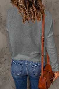 Back view detail of a grey long-sleeved knitted sweater paired with denim jeans.