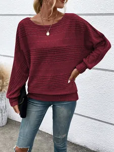 Detailed view of a woman wearing a burgundy textured long sleeve top with blue ripped jeans
