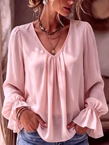 Detail of pink V-neck pleated blouse with elegant ruffled cuffs and soft fabric texture