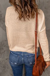 Back view of a casual beige long-sleeve knit sweater paired with denim and a brown leather bag