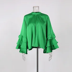 Detailed macro view of elegant green satin blouse featuring multi-layered ruffled bell sleeves