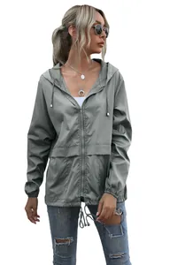 Detail of women's grey lightweight hooded rain jacket for outdoor hiking.