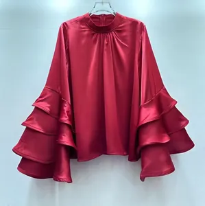 Detail view of red satin blouse featuring tiered ruffled bell sleeves and mock neck